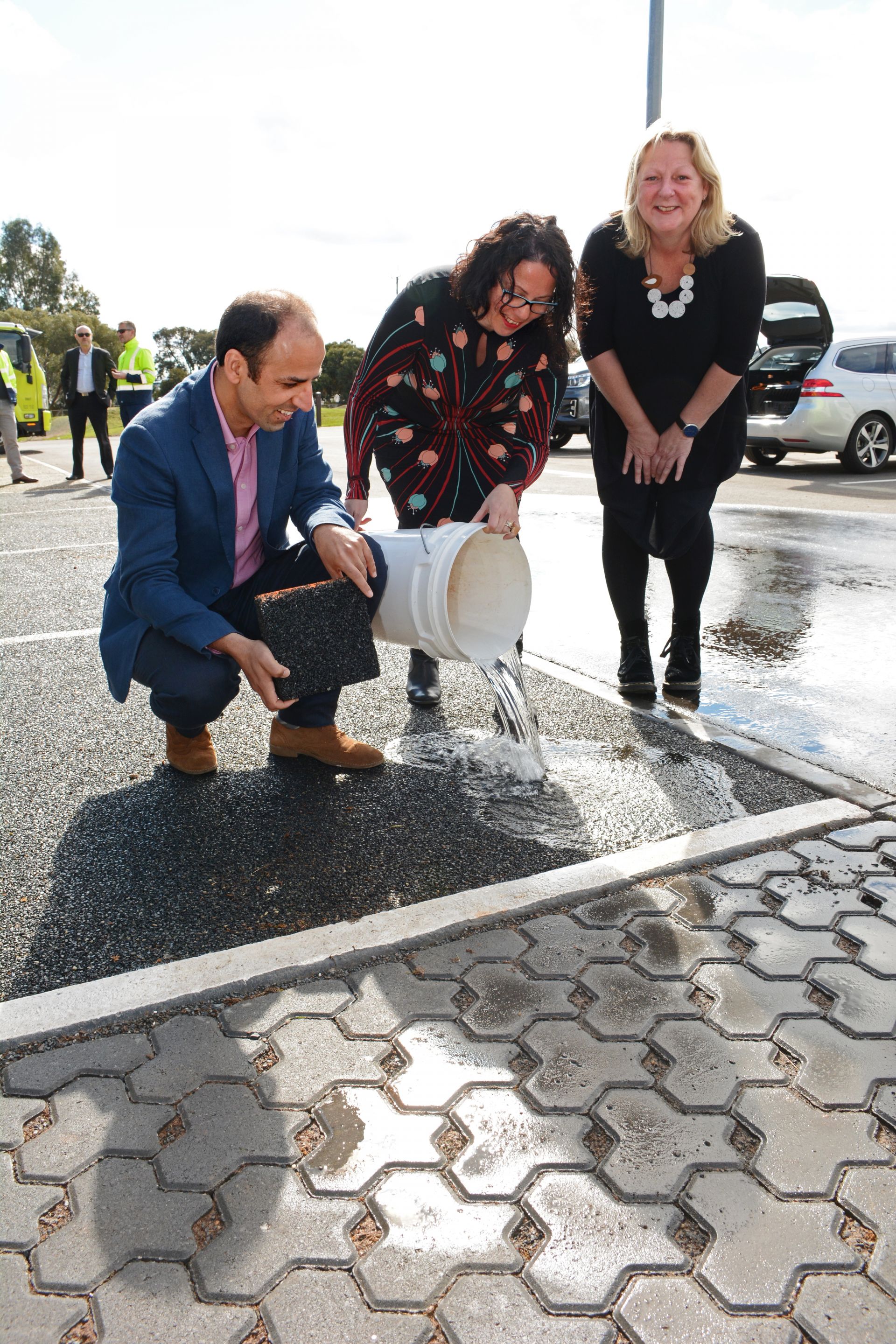 Mahdi Disfani  Senior Lecturer in Geotechnical Engineering at the University of Melbourne, Lina Goodman, Tyre Stewardship Australia CEO and Mayor of the City of Mitcham Dr Heather Holmes-Ross pouring water onto the permeable paving.