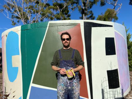Together 2022 an abstract mural located on a water tank in Donald Street Reserve at St Marys with artist Tristan Kerr standing in front of the mural