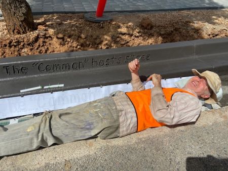 Artist John Denlay writing stories in the wet concrete kerb 
