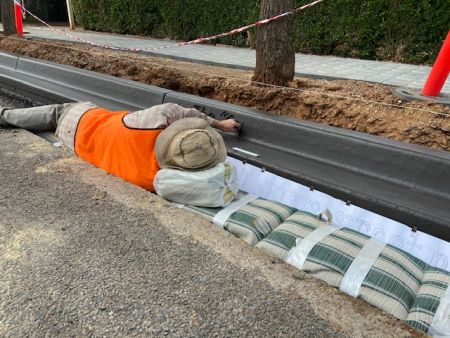 The artist John Denlay lying on Gladys Street drawing a story into the kerbing to create Street Stories